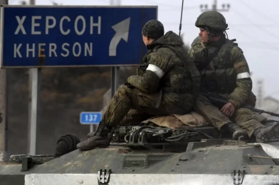 Російські військові на бронетехніці біля дорожнього знаку «Херсон» під час відступу