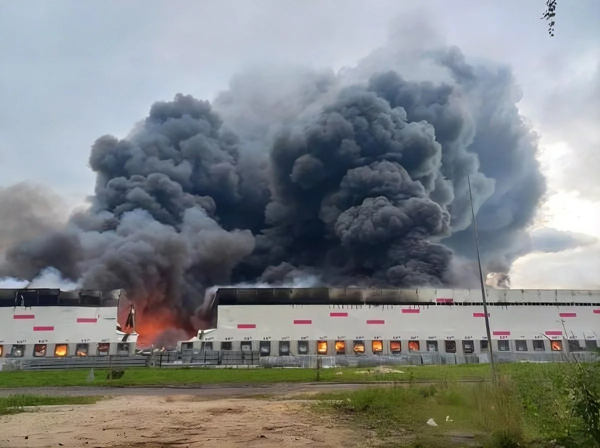 Білий складський комплекс у вогні з потужним стовпом чорного диму