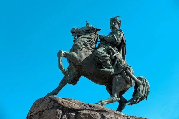 Бронзовий кінний памятник гетьману на скелі під блакитним небом