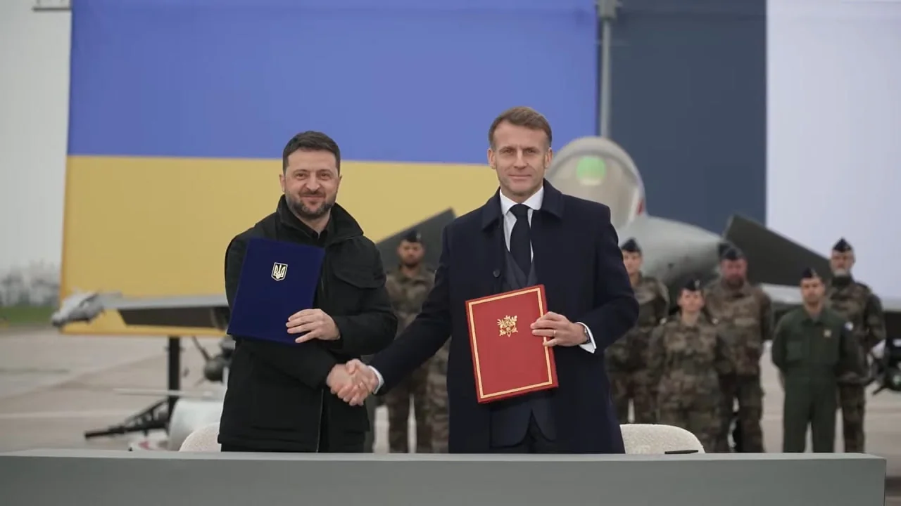Зеленський і Макрон з документами на тлі винищувача та прапора України