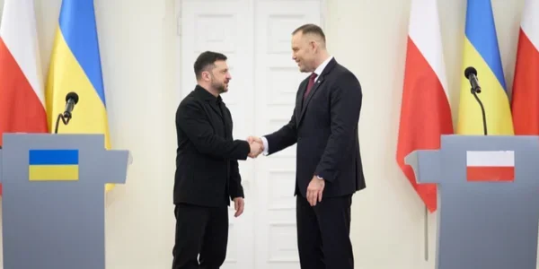 Зеленський і Навроцький тиснуть руки під час зустрічі з прапорами України та Польщі