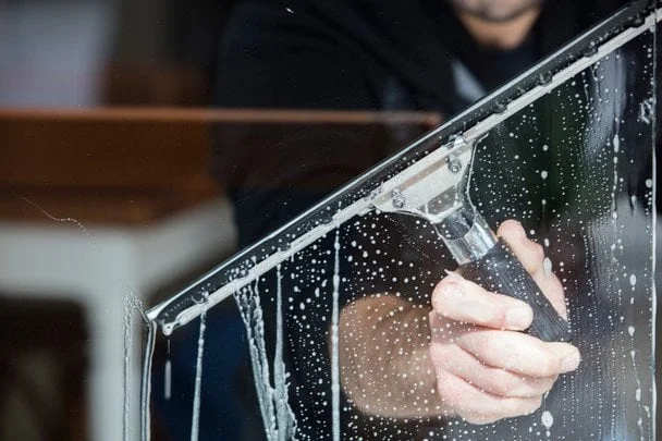 Чемпионат мира по мытью окон: где проходят соревнования, правила и приз Мужчина моет окно скребком среди мыльной пены и пузырьков