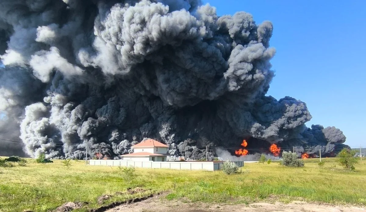 Величезна чорна хмара диму і полумя біля будинку на зеленому полі